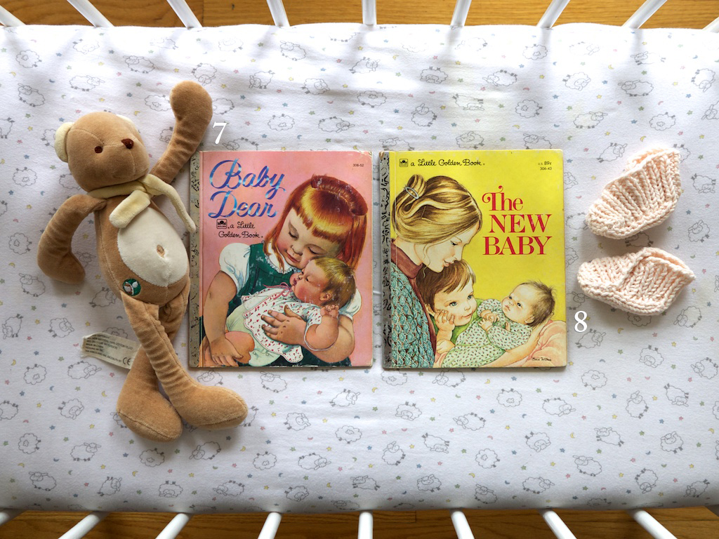 Baby Dear book and The New Baby book in a little white crib with a sheep sheet, booties and a bear on the sides.