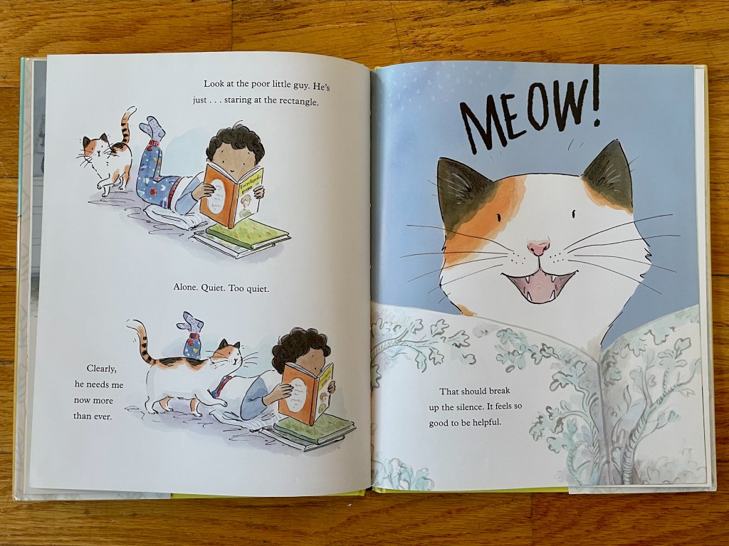 The boy is reading on the floor and the cat sneaks up and surprises him by peeking over the book edge.