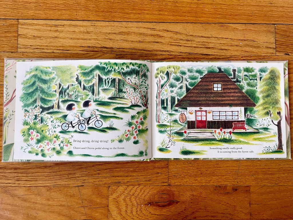 two little girls on bikes riding in the forest up to a little forest house