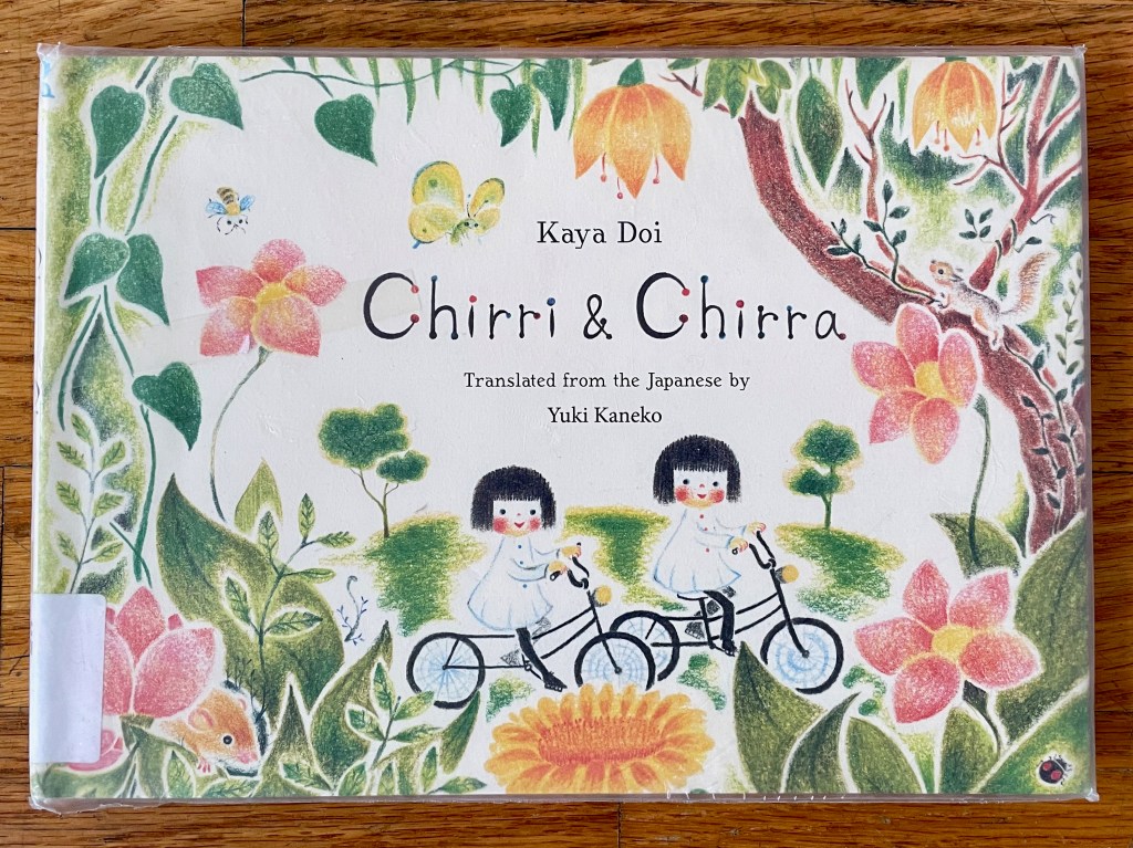 cover of Chirri & Chirra, two little girls with black hair riding on bicycles amongst flowers and trees