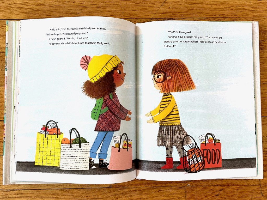 Molly and Caitlin stand facing each other over the gutter of the book with hands reaching out towards each other in an almost embrace. There are bags of food around their feet. Caitlin is a white girl with short reddish brown hair and big black glasses. 