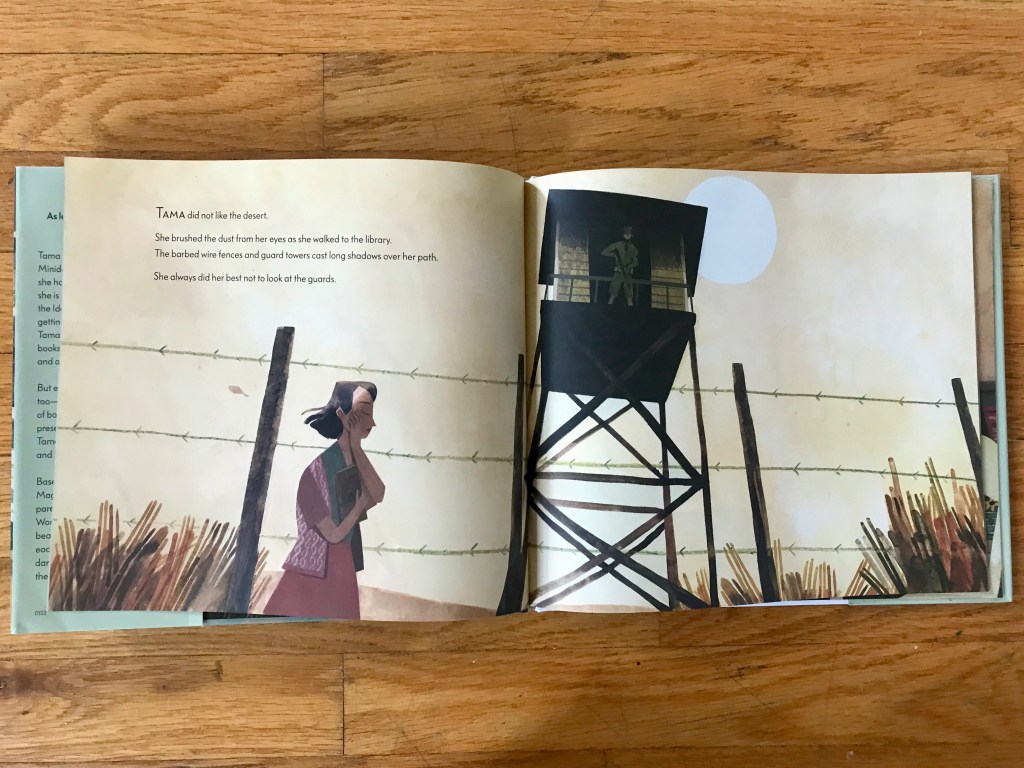 A Japanese woman walks holding a book past a guard tower surrounded by barbed wire.
