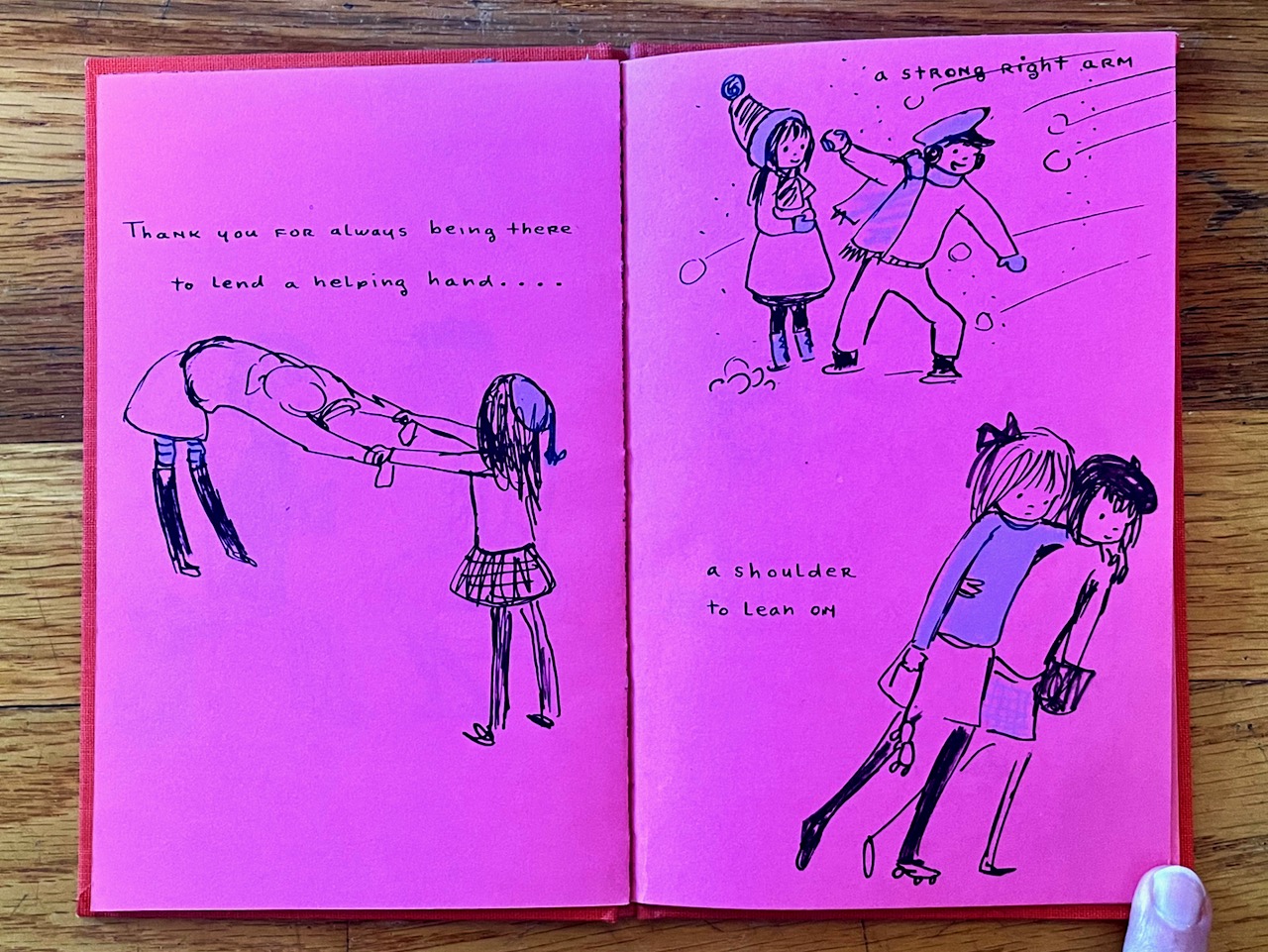 Pink pages of a small book with simple ink drawings of children helping each other with sweaters, throwing snowballs, and walker arm over arm. 